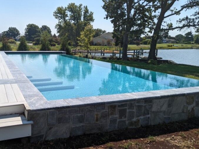 infinity edge pool view from side with trees and lake in background