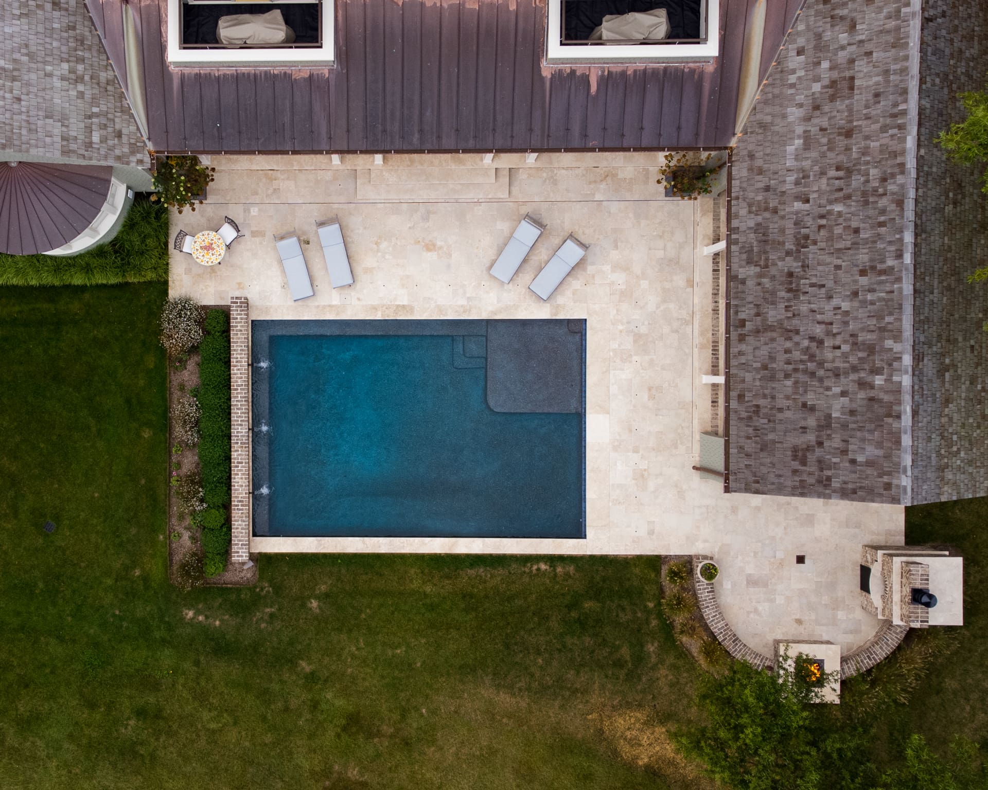 aerial view of pool with water features, fire pit, fireplace