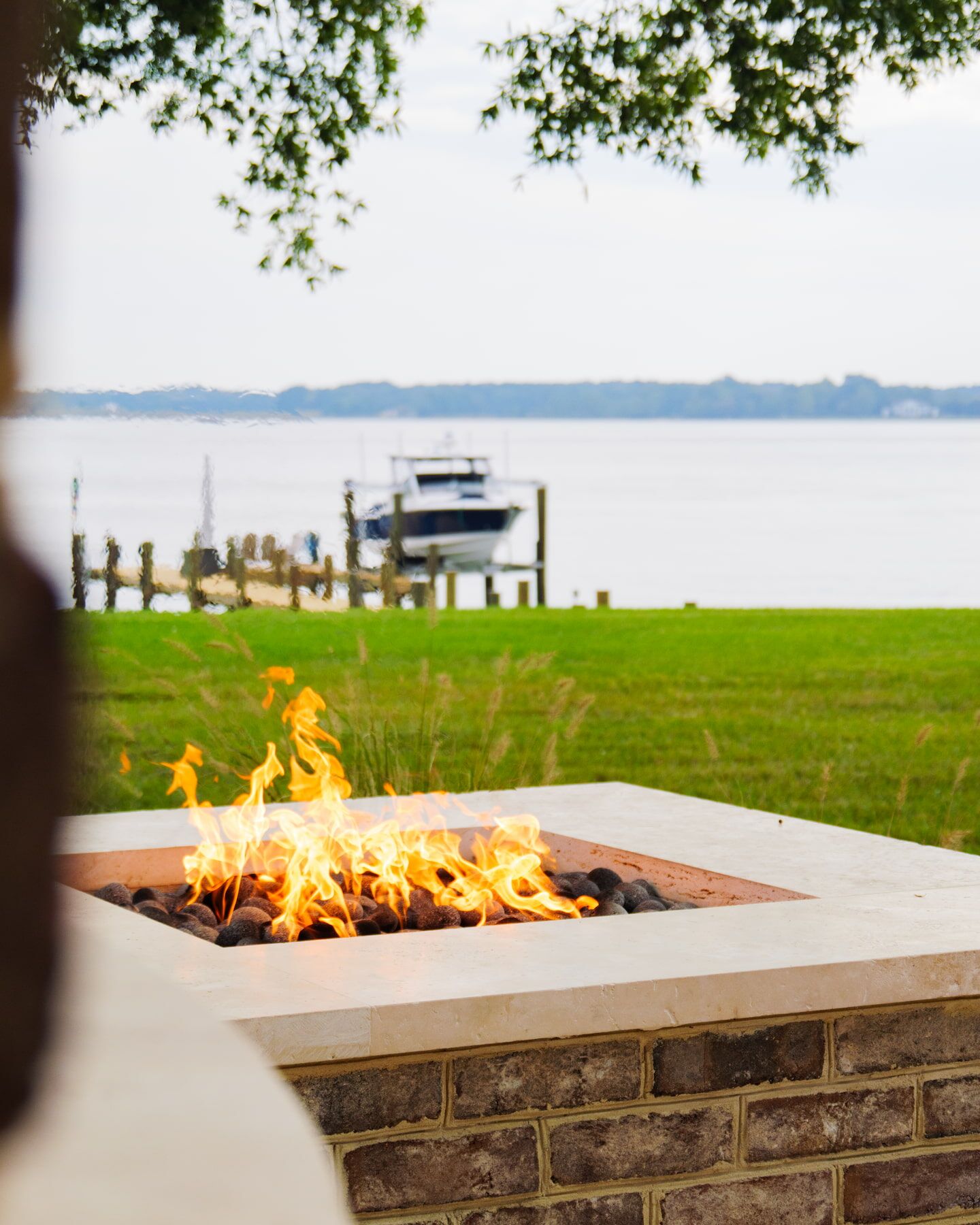 fire pit with flames showing docked boat in water in the background