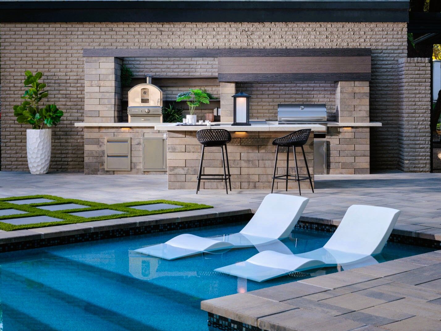 geometric poll with tanning ledge and outdoor kitchen in background