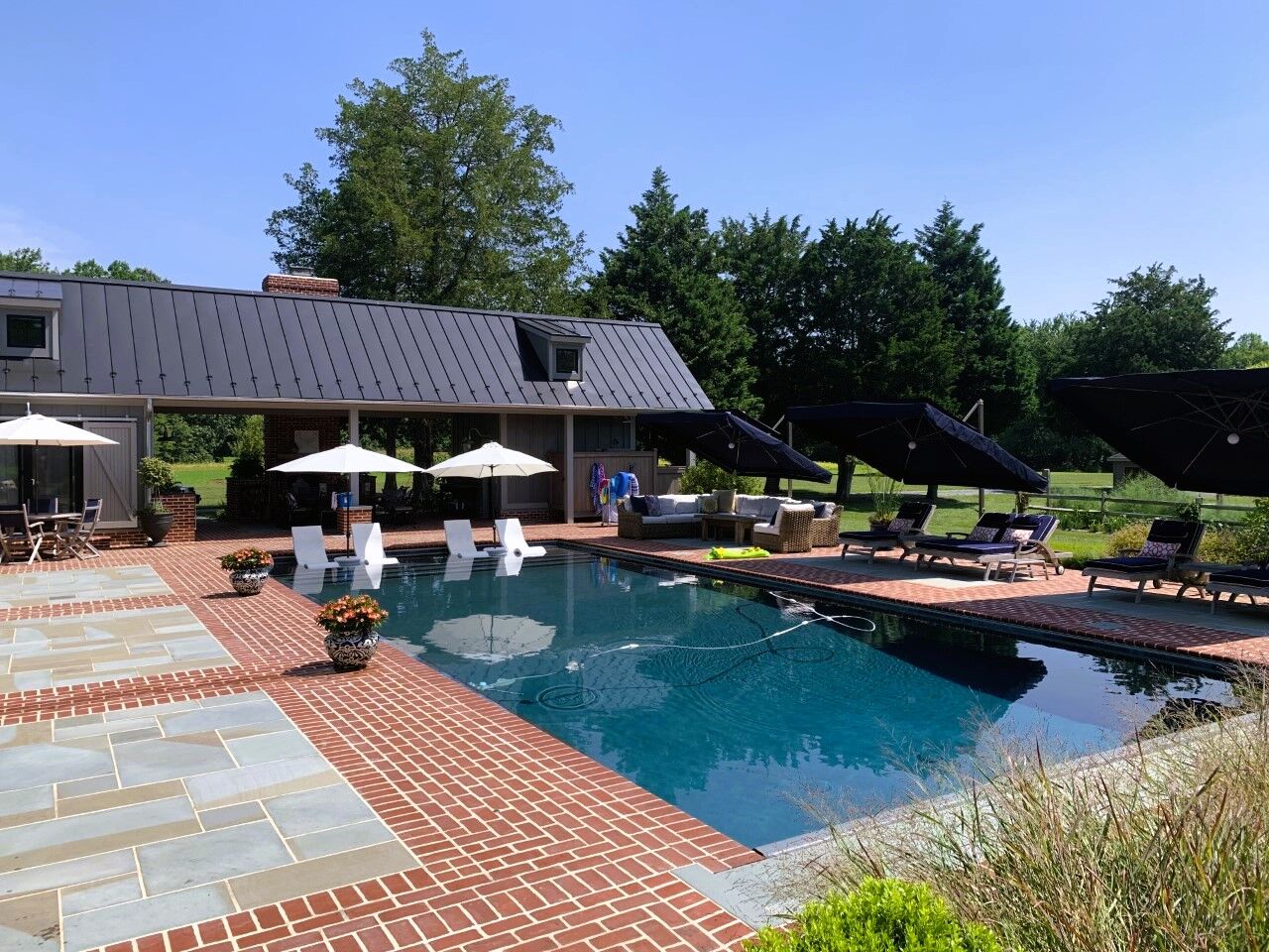 geometric pool with tanning ledge, outdoor seating area, poolhouse