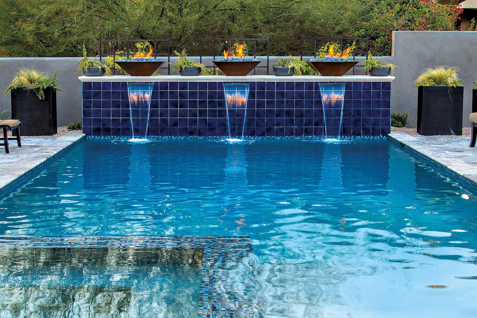 outdoor fire bowls next to geometric pool with water features