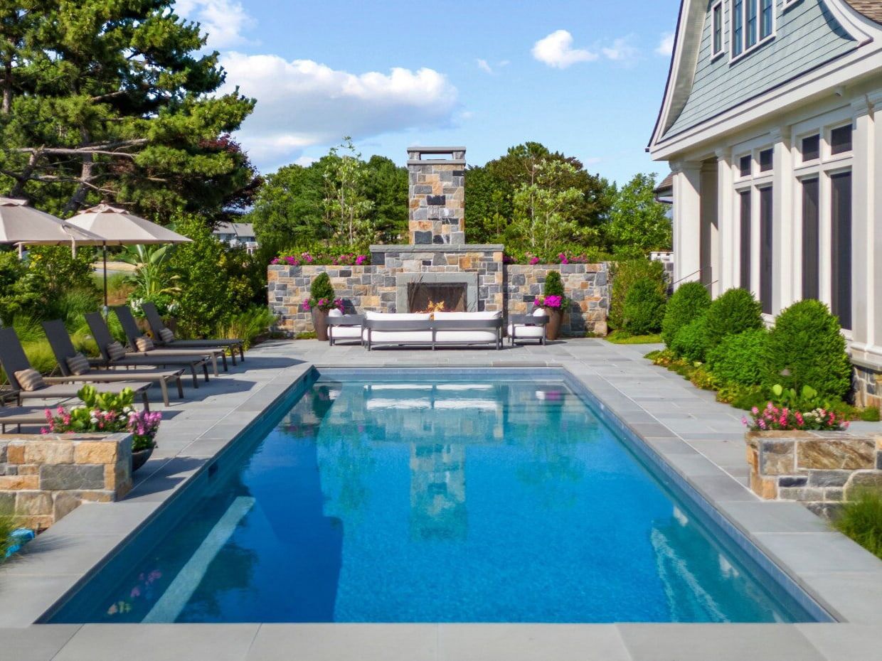 outdoor fireplace next to geometric pool with fireplace showing in pool reflection